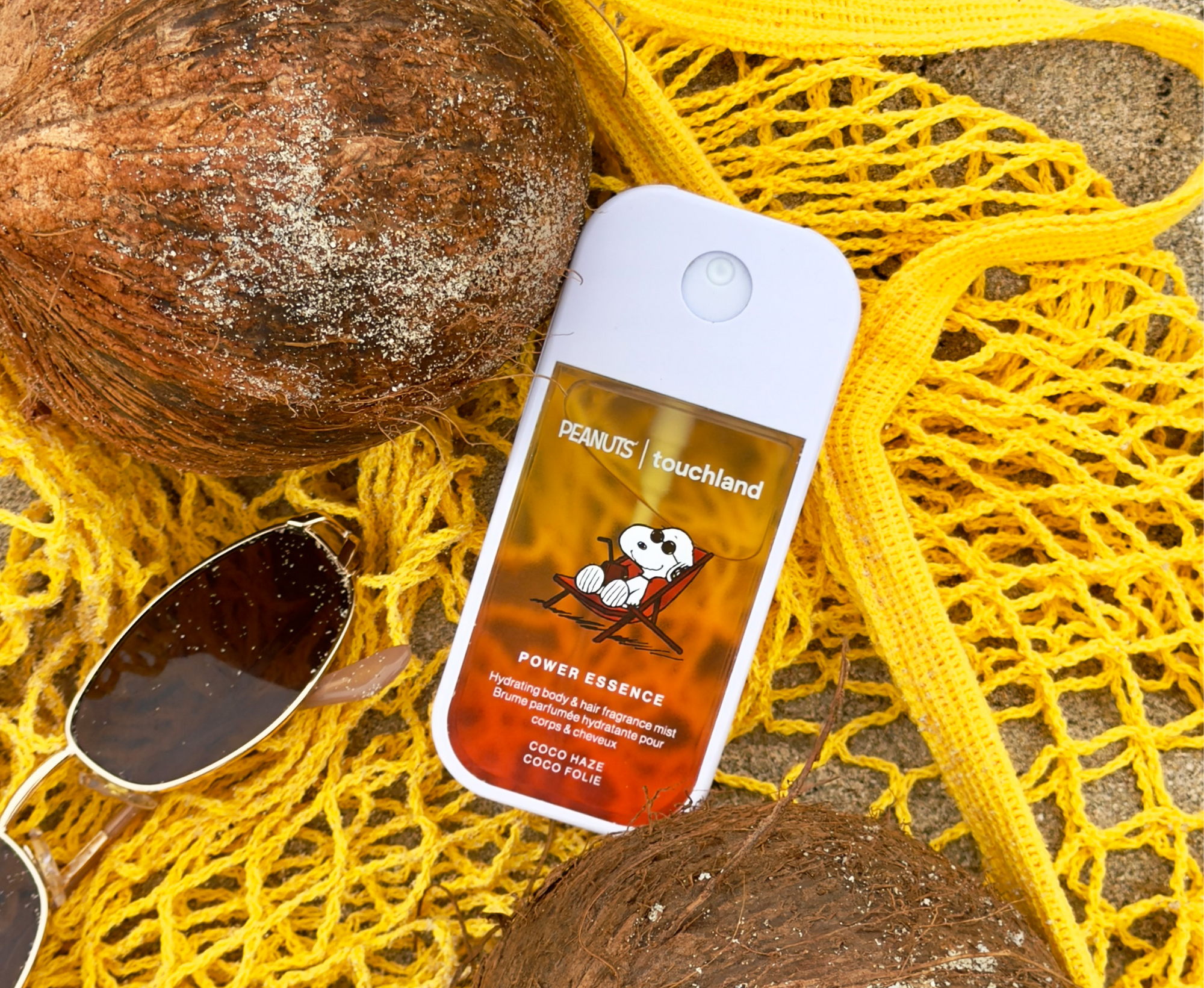 Peanuts x Touchland Power Essence on a beach with sunglasses and coconuts.
