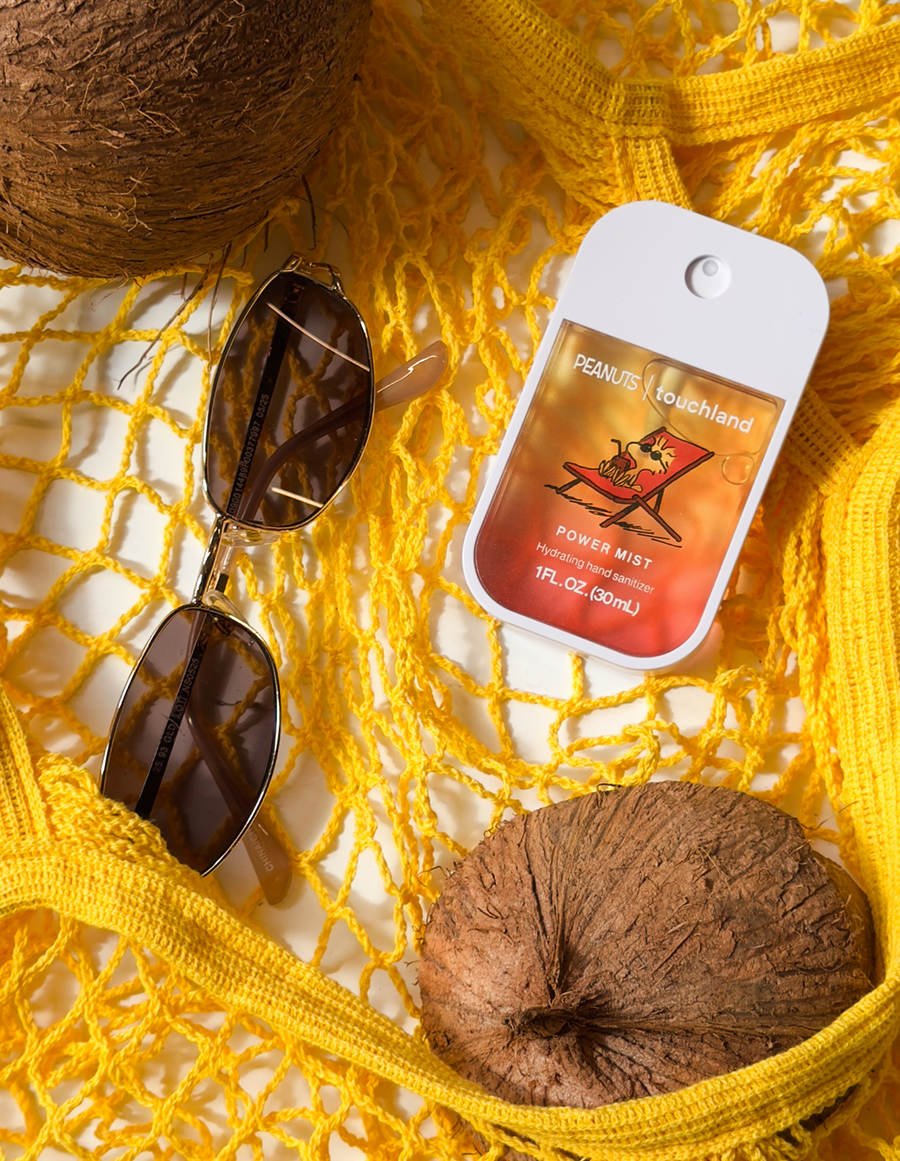 Sunglasses, power mist, and coconuts on a yellow textured surface