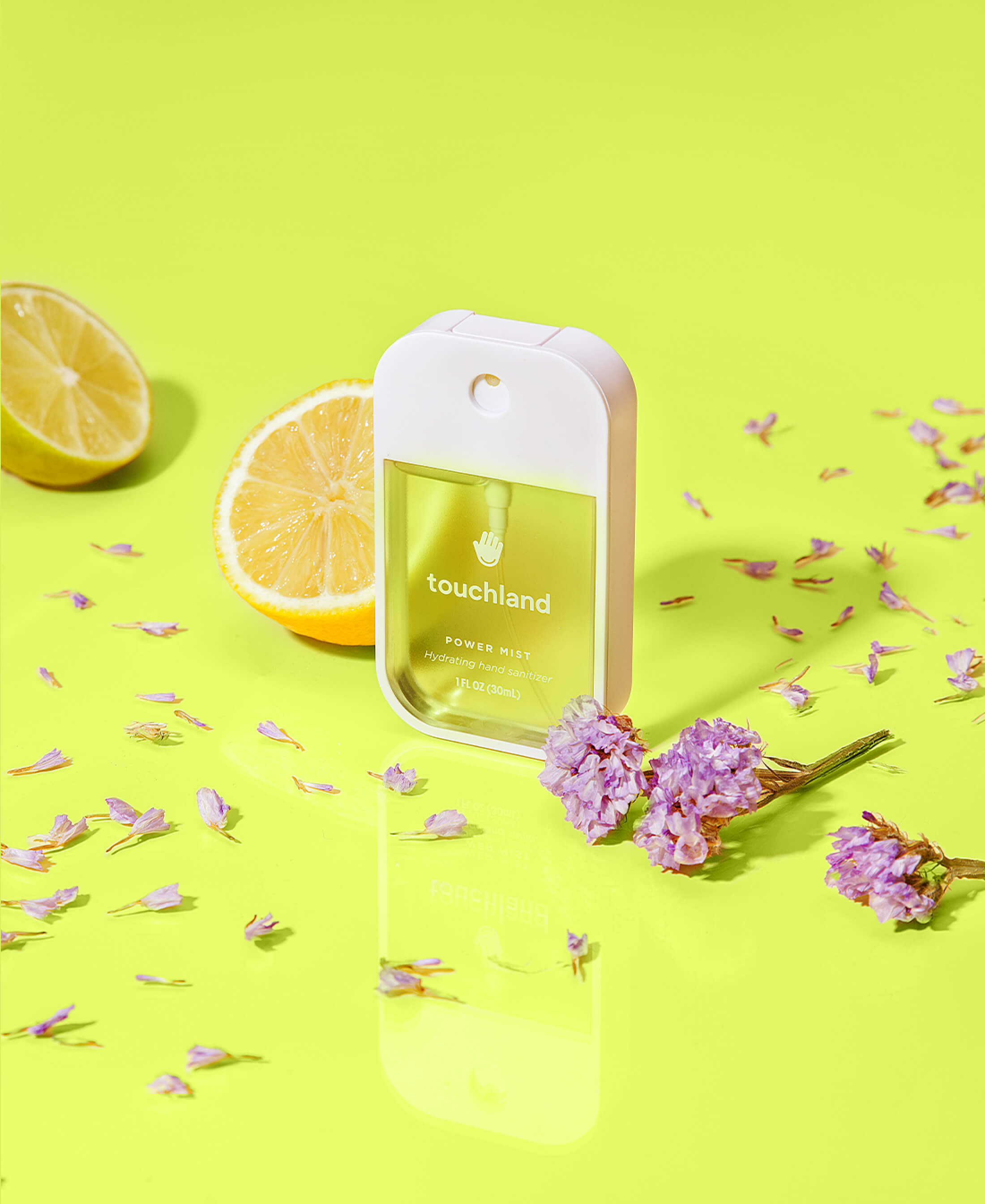 Touchland lemon lime spritz yellow sanitizer on light yellow background with purple flowers and lemons new