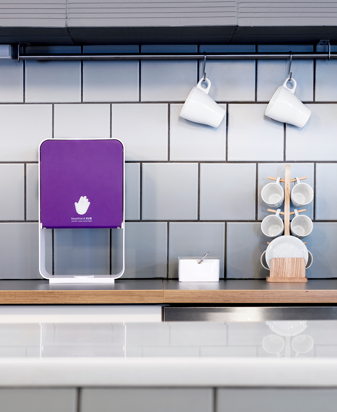Purple kub dispenser in coffee shop on wood table next to mugs