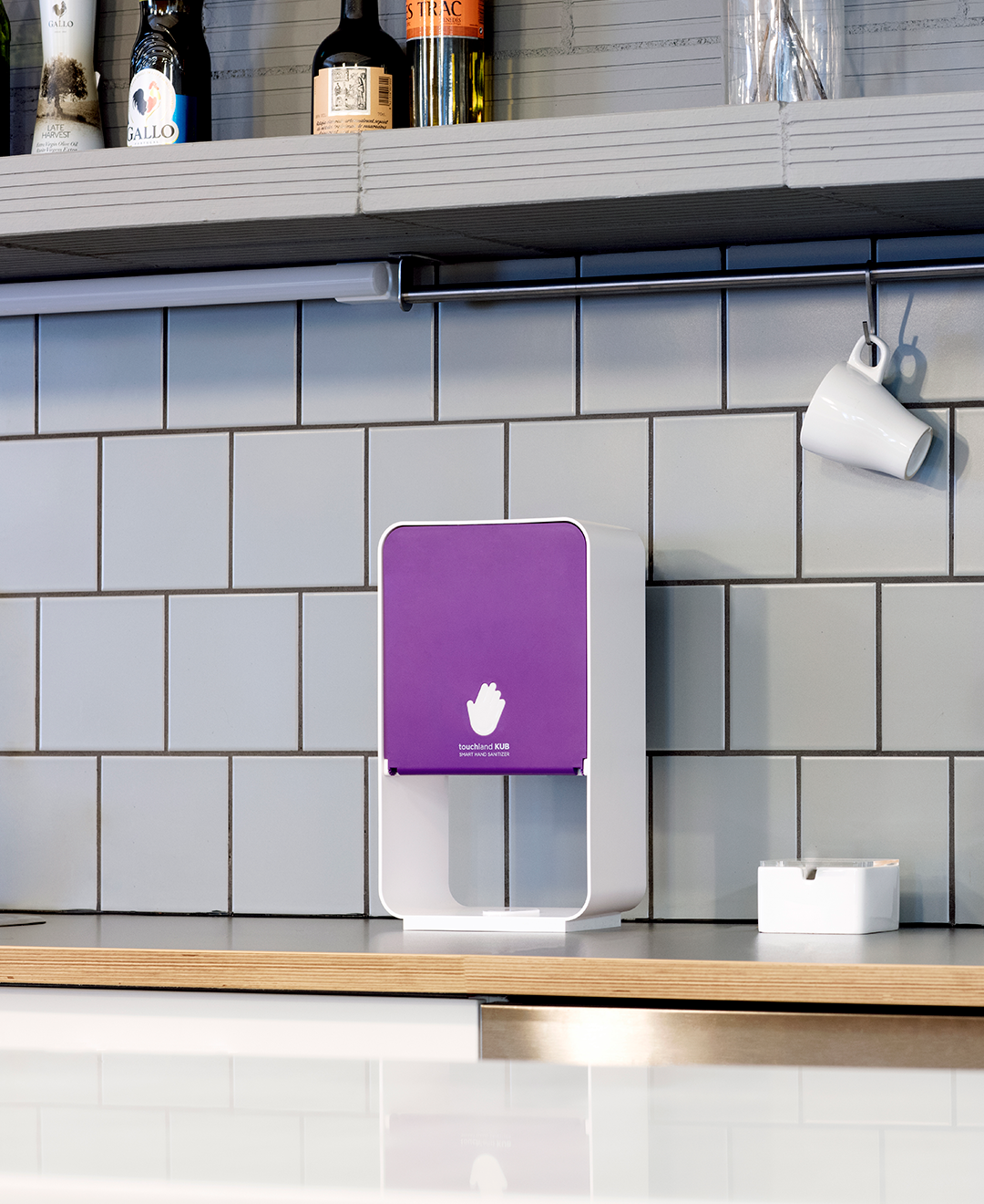 Purple kub dispenser on table on wooden table in coffee shop with mug on walls