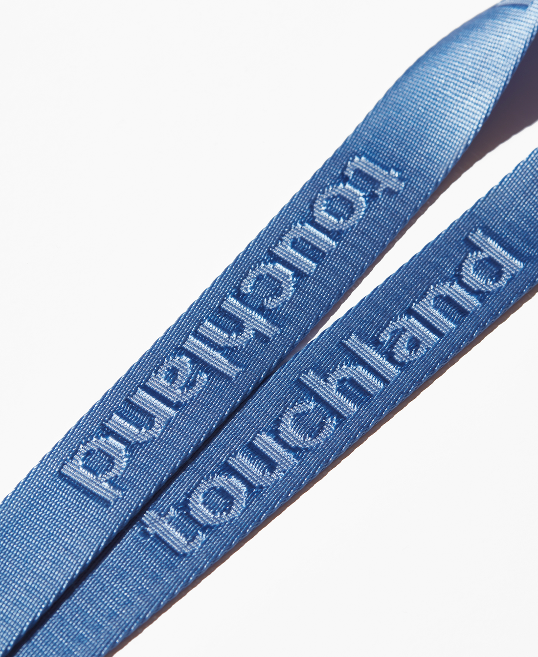 Zoomed in detail shot of touchland text on blue lanyard on white background