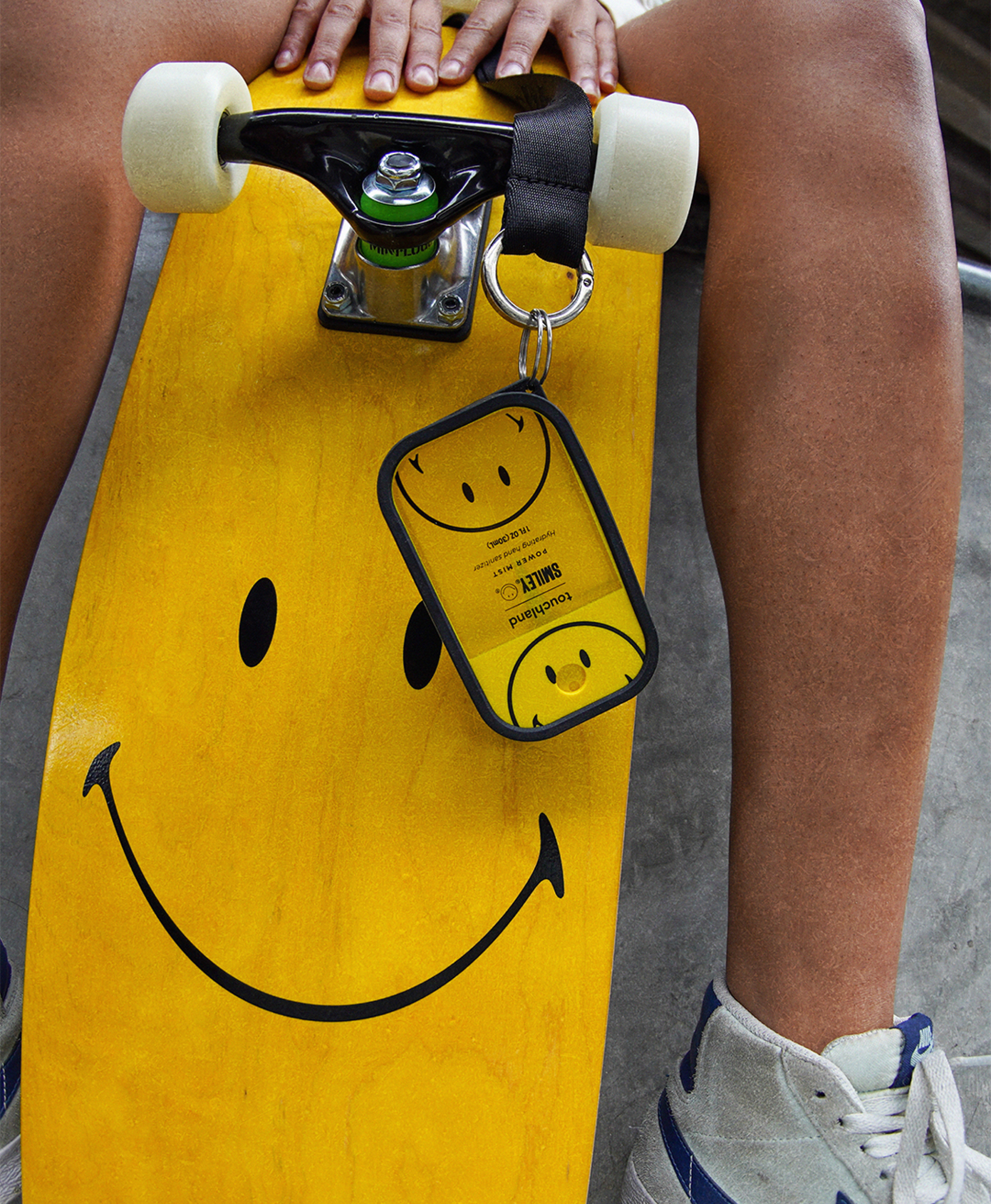 The Smiley Beach Coco Power Mist hanging from a Lanyard on a skateboard.