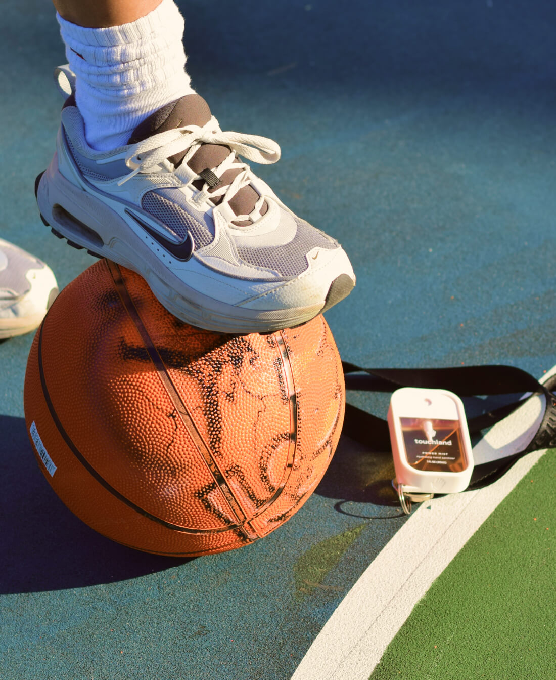 A woman with a foot on customized basketball with our Citrus Grove Power Mist next to it!