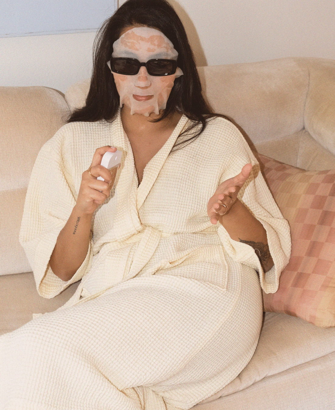 A woman using our Velvet Peach Touchland with a face mask and sunglasses on.