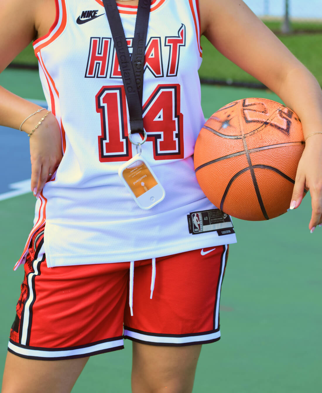 A woman posing with the Citrus Grove Power Mist attached to a black Touchland Lanyard and a customized Touchland basketball.