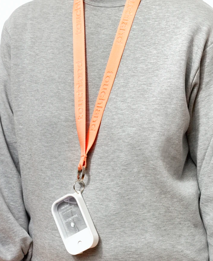 Person wearing grey sweatshirt with peach lanyard around their neck with unscented power mist attached