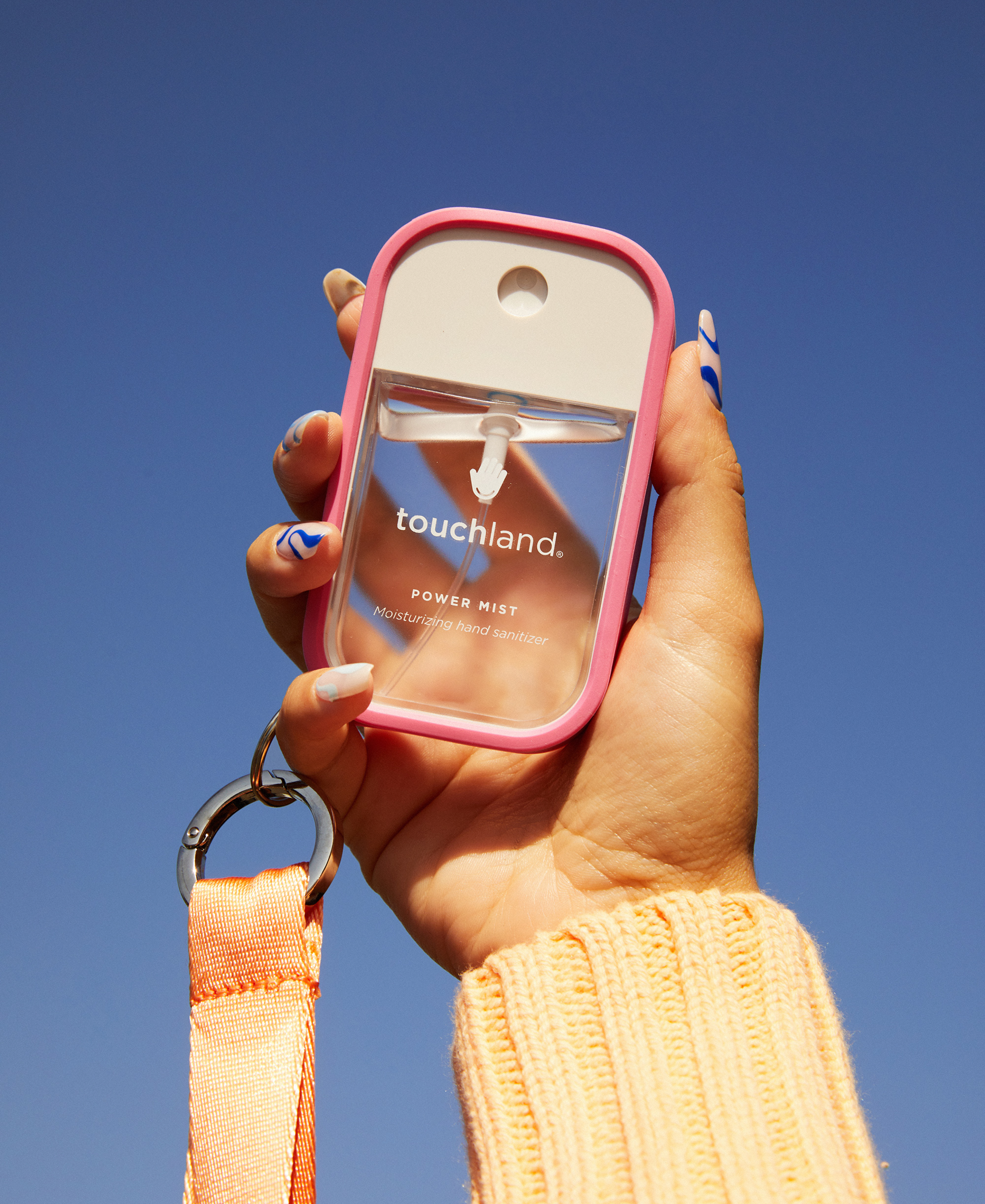 Lady's hand holding a Power Mist hydrating hand sanitizer with a pink case and a lanyard attached