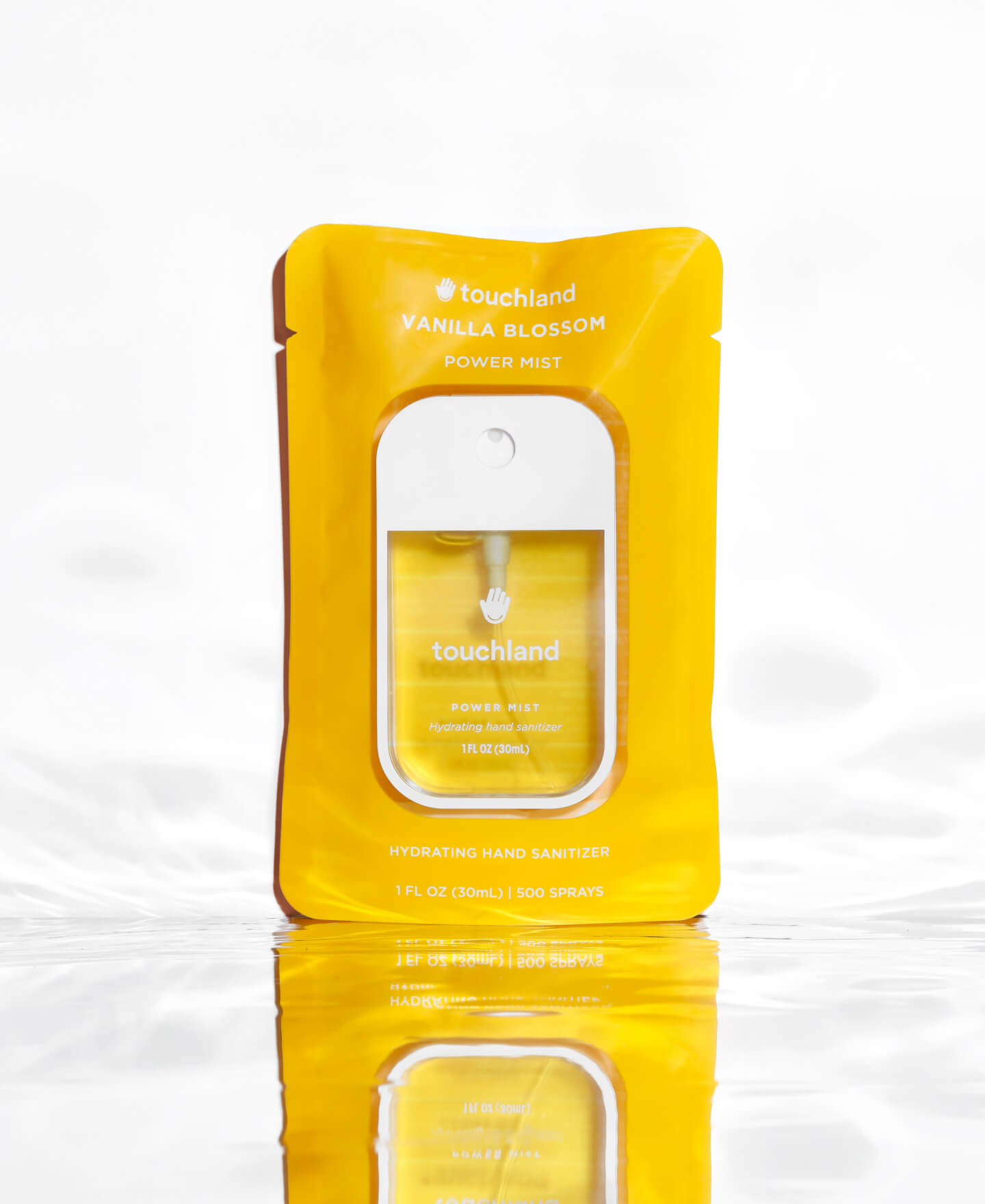 Power Mist hydrating hand sanitizer Vanilla Blossom scented inside yellow packaging standing on a mirror floor with water